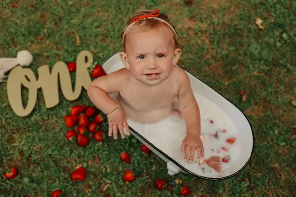 Baby in a white tub with strawberries for a first birthday, outdoor photography by Photoholic, Rockland County NY